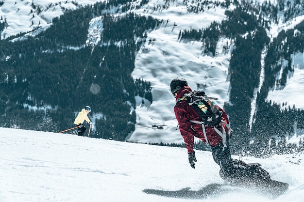 Kostenloses Foto skifahrer beim skifahren auf einem verschneiten berg bei tageslicht