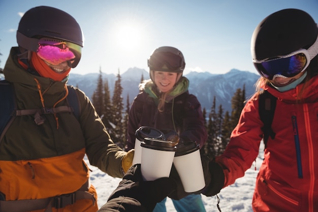 Skifahrer, die eine tasse kaffee auf einem schneebedeckten berg rösten