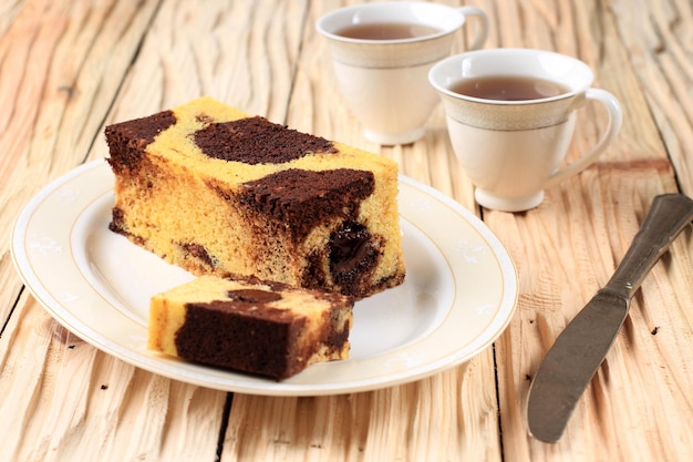 Slice of marble travel cake quadratischer kuchen mit geschmolzener schokolade in der mitte, serviert mit tee Premium Fotos