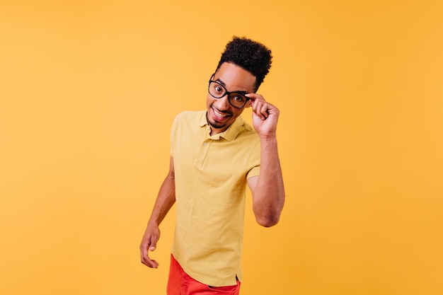 Smarter, stylischer mann, der mit aufgeregtem gesichtsausdruck posiert innenaufnahme eines lustigen männlichen modells in gelbem t-shirt