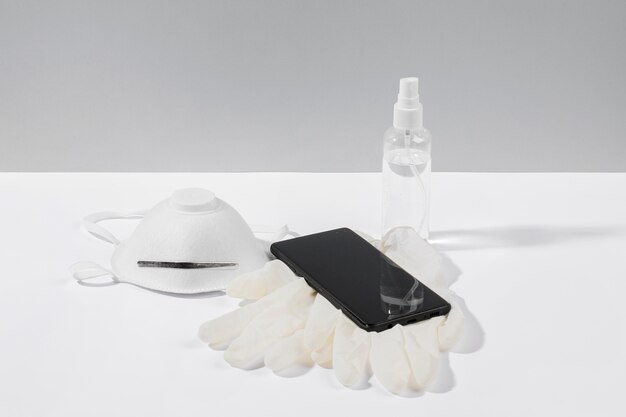 Smartphone auf der Oberfläche mit Gesichtsmaske und OP-Handschuhen