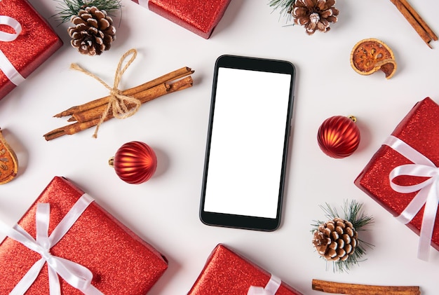 Smartphone mit leerem Bildschirm auf dem Tisch mit Weihnachtsschmuck Draufsicht mit flach liegendem Kopierbereich