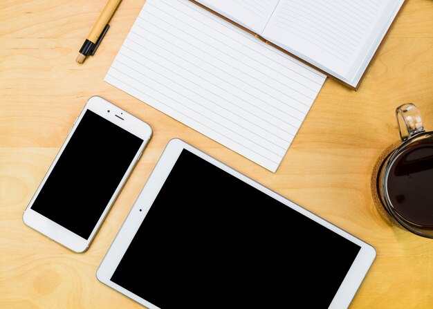 Smartphone und Tablette mit Notizbuch auf Tabelle
