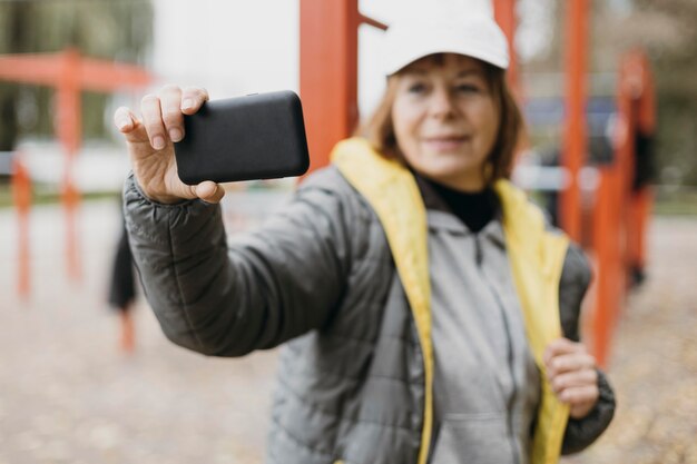 Smiley ältere Frau, die ein Selfie im Freien während des Trainings nimmt