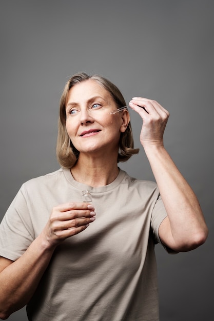 Kostenloses Foto smiley-ältere frau, die mittleren schuss des serums verwendet