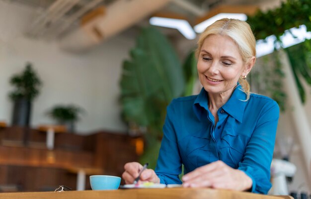 Smiley ältere Geschäftsfrau, die in der Tagesordnung beim Abendessen schreibt