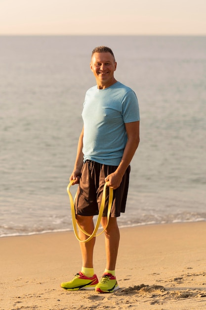 Smiley älterer Mann mit elastischem Seil am Strand