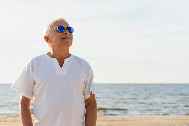 Smiley älterer Mann mit Sonnenbrille genießt seine Zeit am Strand