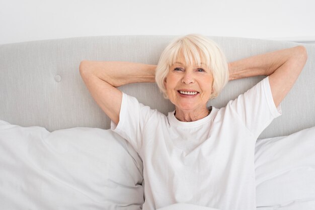 Smiley alte Frau sitzt im Schlafzimmer