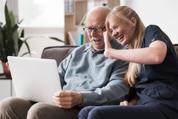 Smiley alter Mann und Krankenschwester, die einen Videoanruf auf Laptop haben