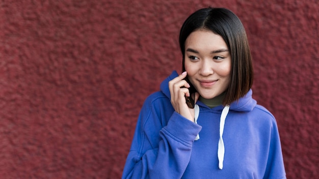 Smiley asiatische Frau, die am Telefon mit Kopienraum spricht