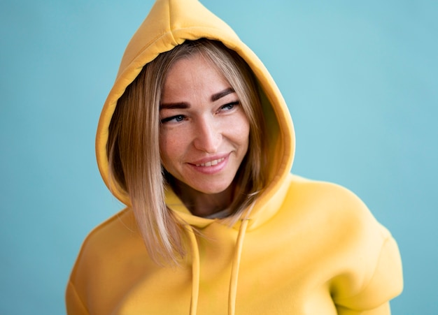 Smiley asiatische Frau, die einen gelben Kapuzenpulli trägt