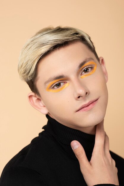 Smiley blonder Mann, der orange Eyeliner trägt