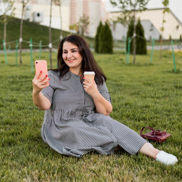 Smiley Brünette Frau macht ein Selfie, während sie ihr Telefon hält