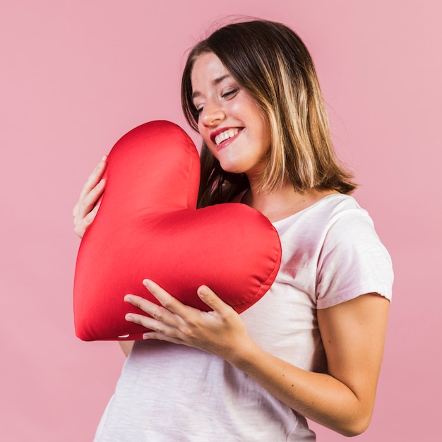 Smiley, der ein Herz geformtes Kissen hält