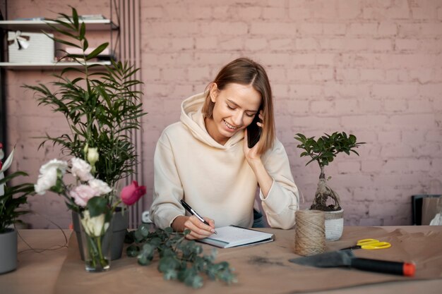 Smiley-Florist mit mittlerer Aufnahme, der am Telefon telefoniert