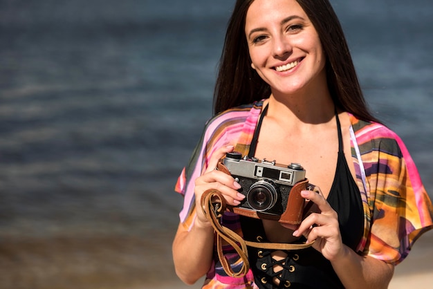 Kostenloses Foto smiley-frau am strand, die kamera hält