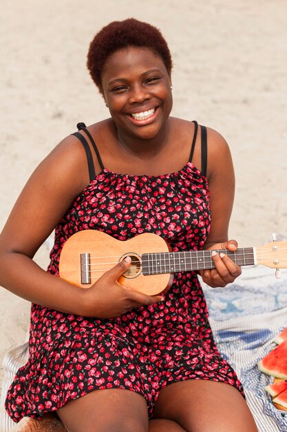 Smiley Frau am Strand mit Gitarre