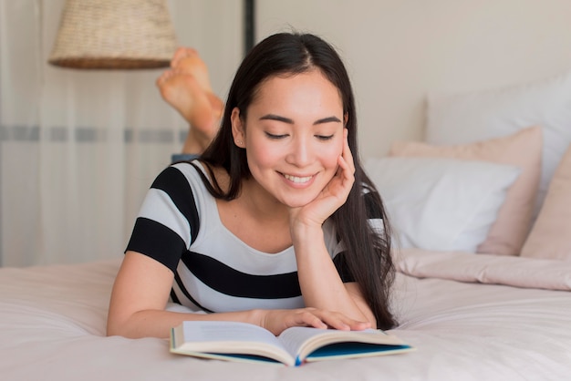 Kostenloses Foto smiley-frau beim lesen im bett