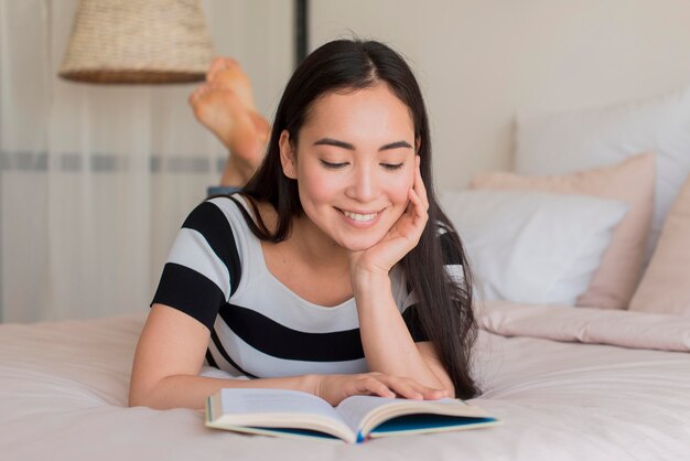 Smiley-Frau beim Lesen im Bett