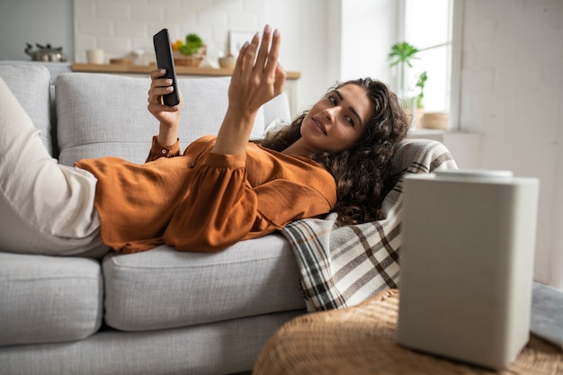 Kostenloses Foto smiley-frau der seitenansicht, die auf der couch liegt