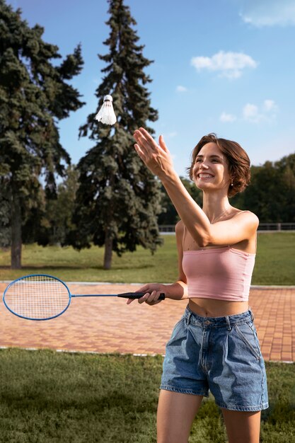 Smiley-Frau der Seitenansicht, die Badminton spielt