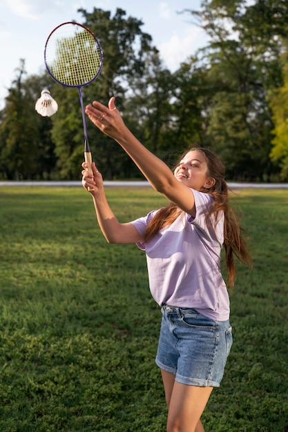 Smiley-Frau der Seitenansicht, die Badminton spielt