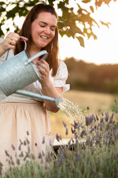 Smiley-Frau der Seitenansicht, die Blumen gießt