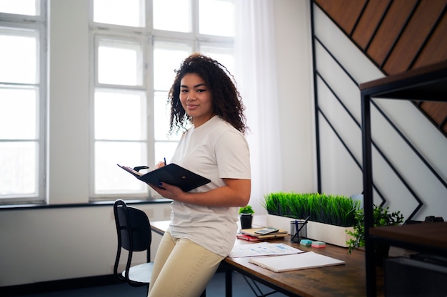 Smiley-Frau der Seitenansicht, die im Büro arbeitet