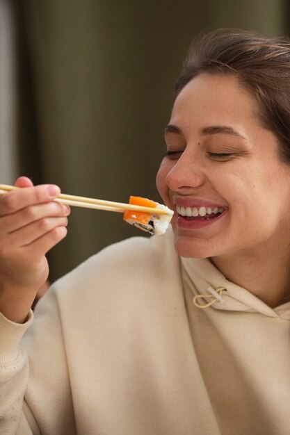 Smiley-Frau der Seitenansicht, die Sushi isst