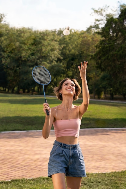 Smiley-Frau der Vorderansicht, die Badminton spielt