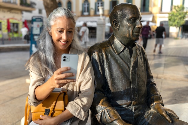 Kostenloses Foto smiley-frau der vorderansicht, die in der nähe der statue posiert