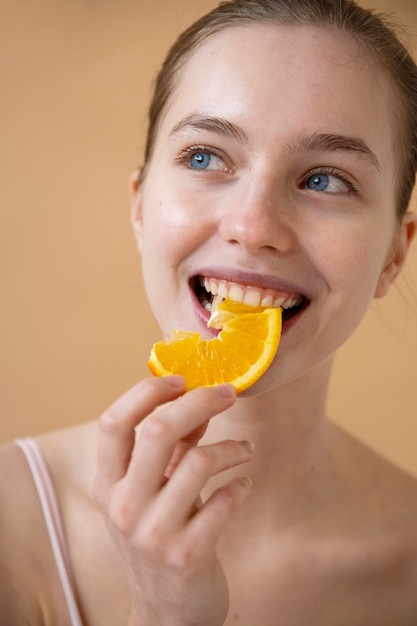 Smiley-Frau der Vorderansicht, die Orange isst