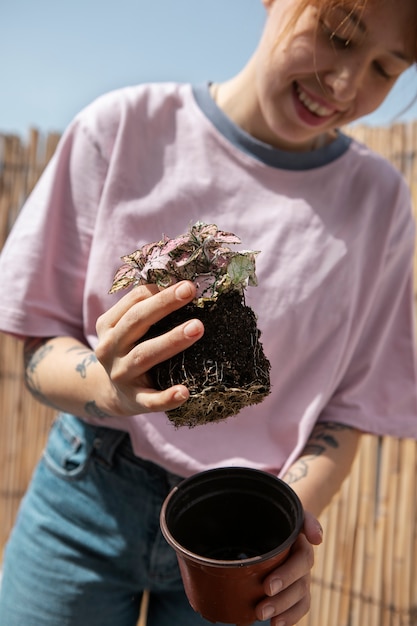 Kostenloses Foto smiley-frau der vorderansicht, die pflanze umpflanzt
