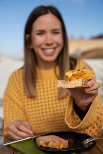 Kostenloses Foto smiley-frau der vorderansicht, die spanische tortilla hält