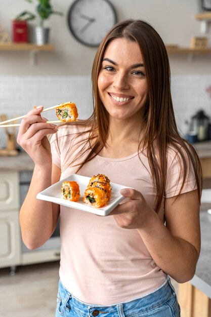 Smiley-Frau der Vorderansicht, die Sushi isst
