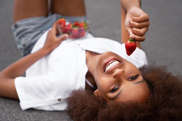 Smiley-Frau des hohen Winkels, die Erdbeeren isst