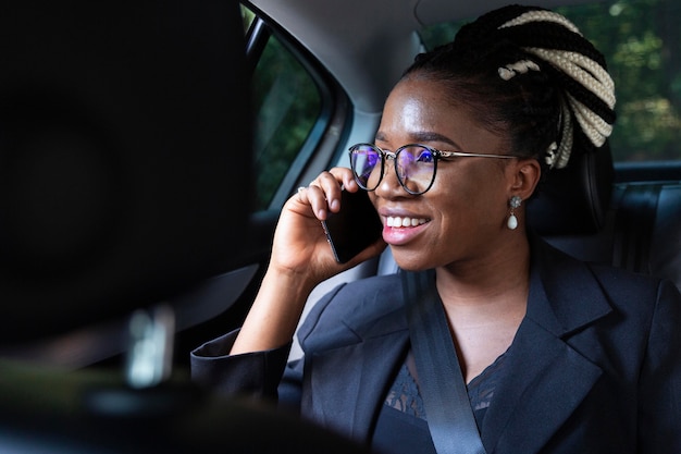 Smiley-Frau, die auf Smartphone spricht, während in ihrem Auto