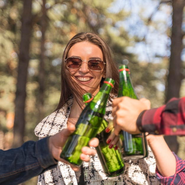 Kostenloses Foto smiley-frau, die bier mit ihren freunden draußen röstet