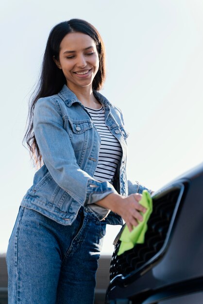 Smiley-Frau, die draußen ihr Auto putzt