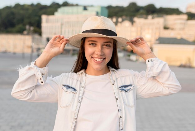 Smiley-Frau, die draußen mit Hut während des Reisens aufwirft