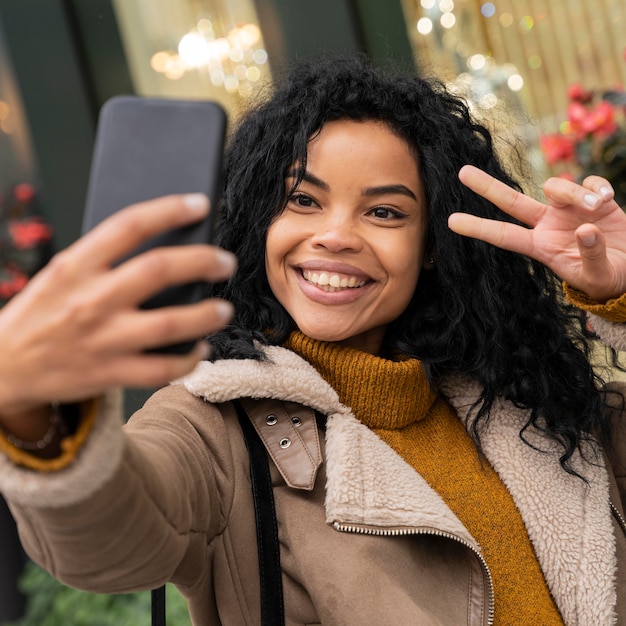 Smiley-Frau, die ein selfie mit ihrem Smartphone draußen nimmt