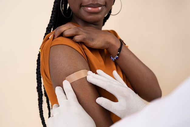 Kostenloses Foto smiley-frau, die einen aufkleber am arm erhält, nachdem sie einen impfstoff erhalten hat