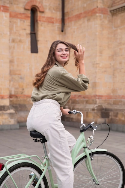 Kostenloses Foto smiley-frau, die ihr fahrrad in der stadt reitet