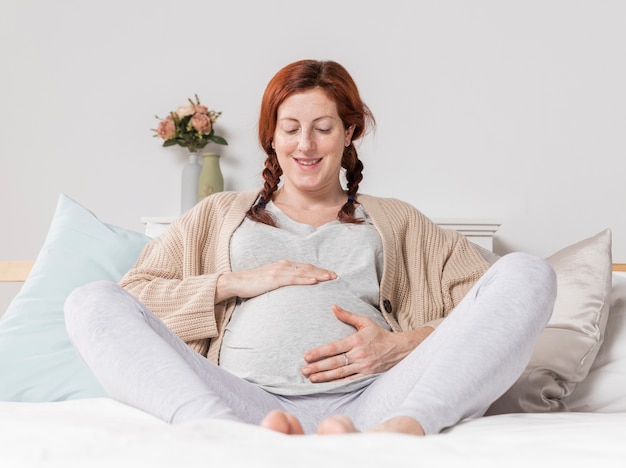Smiley-Frau, die ihren schwangeren Bauch berührt