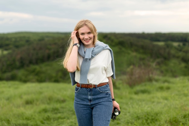 Kostenloses Foto smiley-frau, die in der natur beim halten der kamera aufwirft