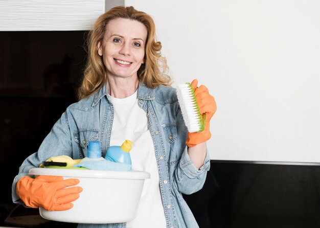 Kostenloses Foto smiley-frau, die korb der reinigungsprodukte und der bürste hält