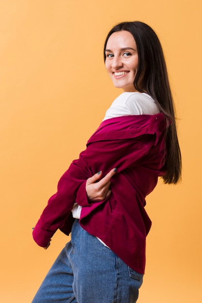 Kostenloses Foto smiley-frau, die mit einem orange hintergrund aufwirft