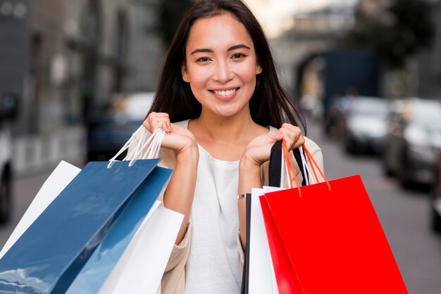 Smiley-Frau, die mit Einkaufstaschen nach dem Kaufkauf aufwirft