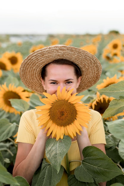 Smiley-Frau, die mit Sonnenblume aufwirft